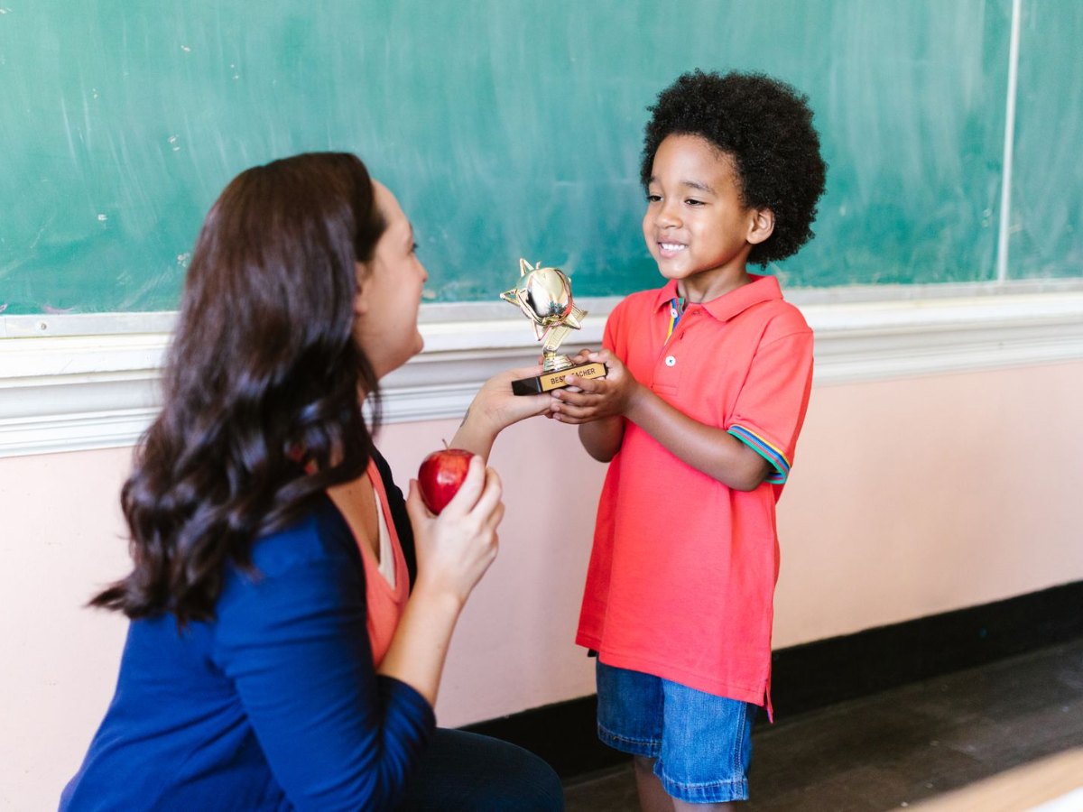 Teacher presenting a trophy to a smiling child